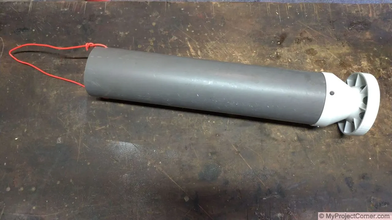 La mangeoire à poulets vissée au tuyau en pvc et le fil de fer suspendu